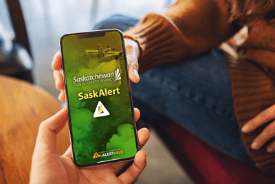 SaskAlert app on mobile device with a person holding it