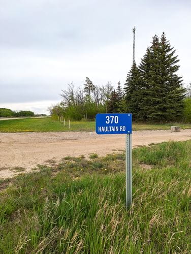 Blue rural address sign in front of a tree